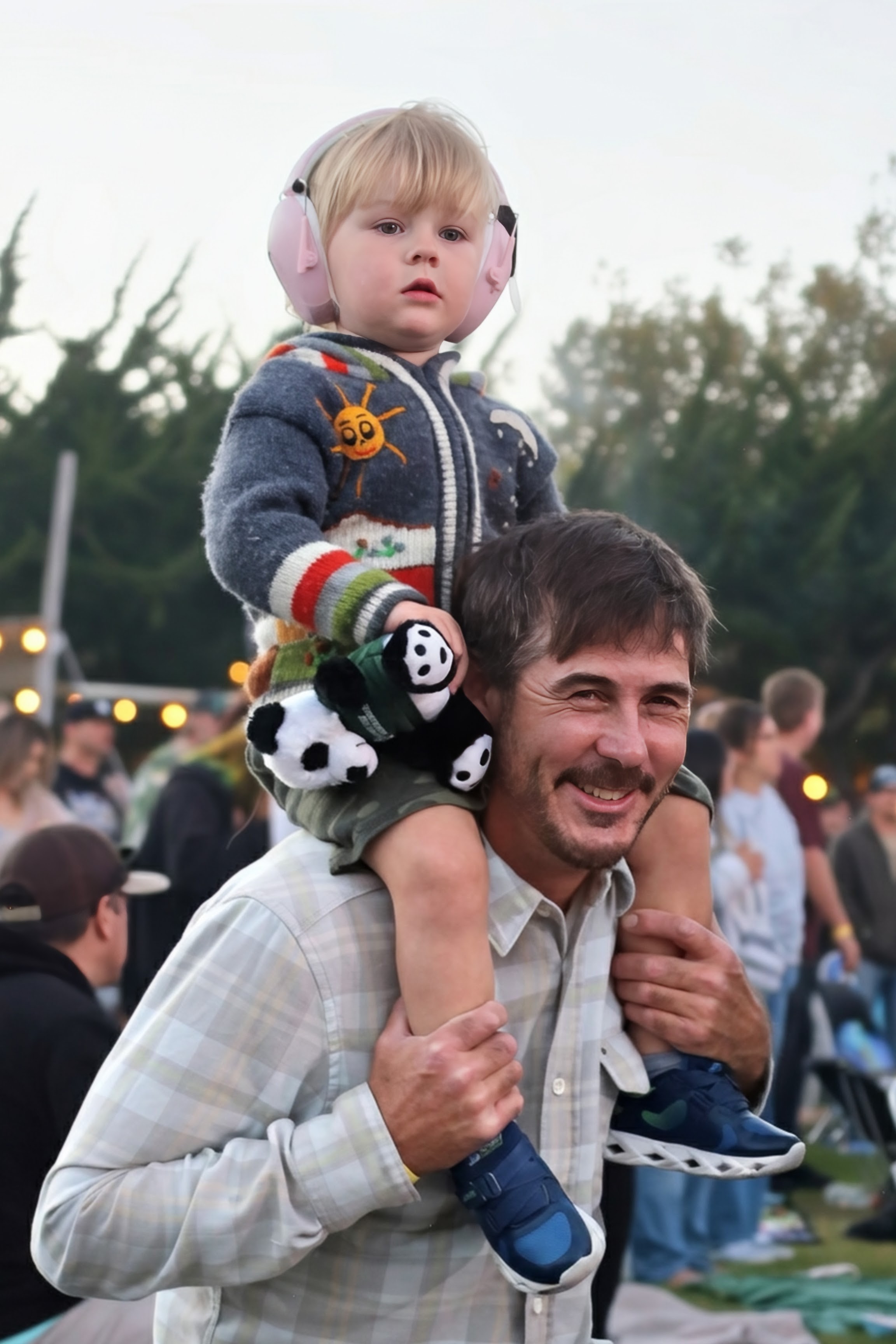 Dad with toddler on shoulders wearing pink ear muffs