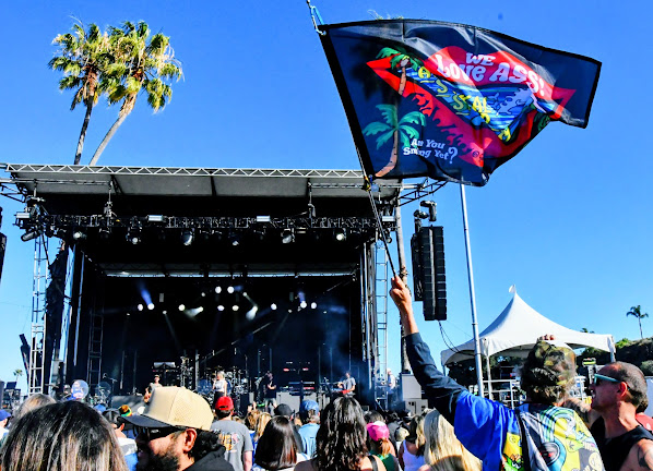 Jimmy J flying his flags against a blue sky with the stage behind him